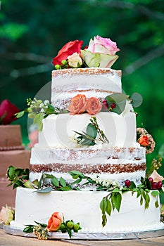 A chocolate wedding cake with white frosting and red, pink, and orange flowers with green leaves - wedding cake series