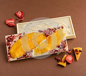 Chocolate white fruit whole tile decorated with slices of fruit nuts and slices on a brown background. Minimalism food