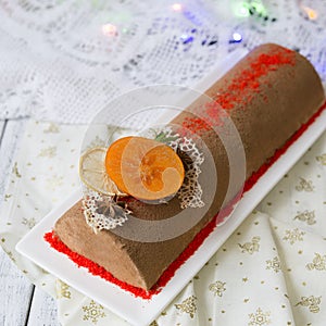 Chocolate yule log christmas cake, also know as Buche de Noel, with tangerine mousse decorated with persimmon, orange photo