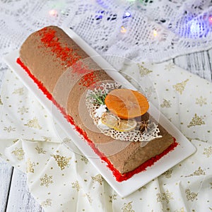 Chocolate yule log christmas cake, also know as Buche de Noel, with tangerine mousse decorated with persimmon, orange photo