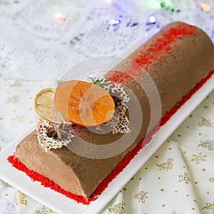 Chocolate yule log christmas cake, also know as Buche de Noel, with tangerine mousse decorated with persimmon, orange photo