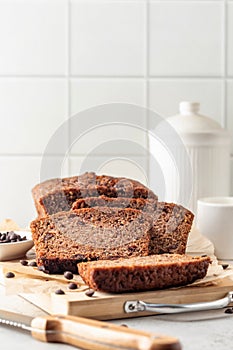Chocolate zucchini bread cake sliced. Moist chocolate cake with grated zucchini, cocoa and chocolate chips on white tile kitchen