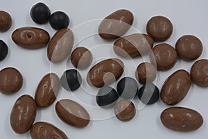 Chocolates, peanuts, nuts, raisins covered with chocolate glaze, milk and dark chocolate pebbles.