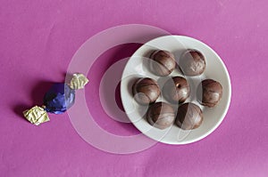 Chocolates in a white porcelain saucer on a pink background