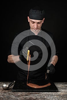 Chocolatier in black uniform in the process of making chocolates photo