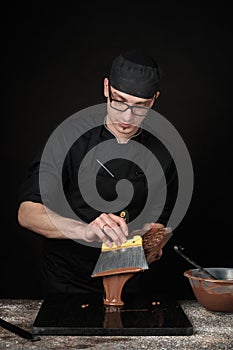 Chocolatier in black uniform in the process of making chocolates photo