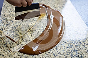 Chocolatier stirs the tempered chocolate on a granite table in order to cool