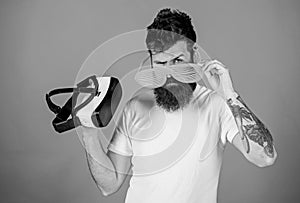 Choice between reality and VR. Man bearded hipster with virtual reality headset and louvered sunglasses on red photo