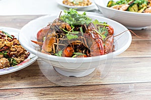 Chongqing Sichuan spicy dried chilli small lobsters, among other dishes in the background. Food photography at Chinese restaurant