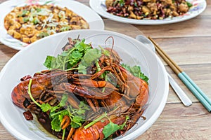 Chongqing Sichuan spicy dried chilli small lobsters, among other dishes in the background. Food photography at Chinese restaurant