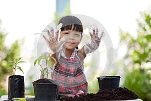 Choose focus on the little gardener`s hands. cute face kid girl Wear white plastic gloves stained with dirt. put your hands