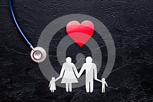 Choose health insurance. Stethoscope, paper heart and silhouette of family on black stone background top view copyspace