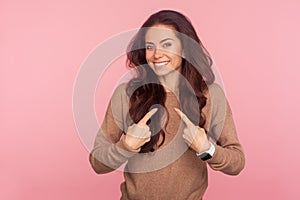 Choose me, I`m best! Portrait of optimistic boastful young woman with brunette wavy hair pointing herself