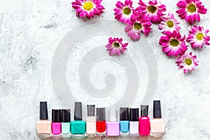 Choose nail polish for manicure. Bottles of colored polish on grey background top view copyspace