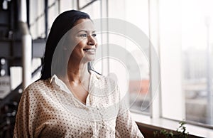 Choose to see the positivity in each day. a mature businesswoman looking out a window in an office.