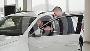 choosing automobile, car sales manager telling young successful man about new vehicle model in auto showroom