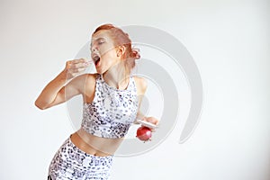 Choosing between fruits and sweets of health caucasian woman in black and white sportswear holding apple and strawberry cake with