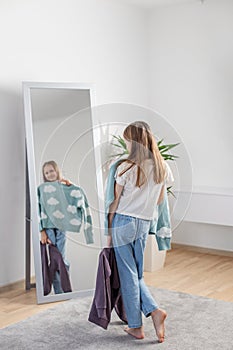 Choosing Outfits: Child with Clothes by Mirror. Morning preparation before school