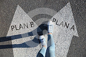 Choosing between Plan A and Plan B. Woman near arrows on road, above view