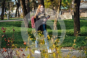 Choosing a university, college. Female college student with books and laptop outdoors. Redhead college student girl with
