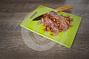 Chopped Bacon on a green cutting board with a carving knife