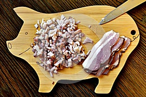 Chopped bacon and sliced bacon on pig shape bamboo kitchen desk. Pork bacon and funny smilling pig kitchen board. Knife