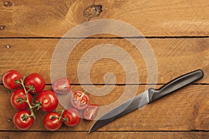 Chopped bunch tomatoes and knife on wood