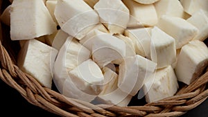 Chopped cassava (yucca) sliced root in rustic rattan bowl on a wooden table