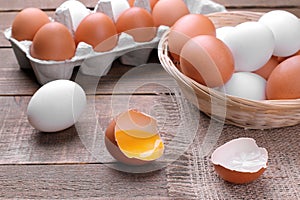 Chopped chicken egg with yolk close-up next to eggs in basket and tray on brown background