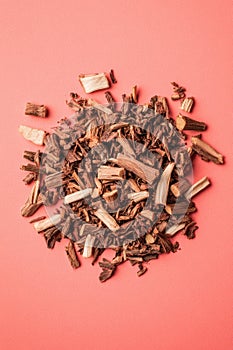 Chopped cinnamon sticks piled on vibrant red background for spices and aromatherapy photo