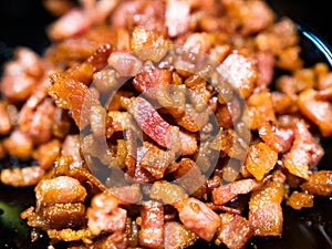 Chopped, crispy fried bacon on black background