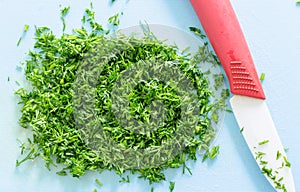 Chopped dill. Ceramic Knife on blue cutting board