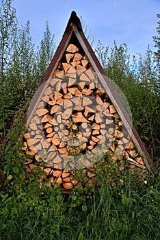 Chopped firewood stacked in rows stacked under triangular roof