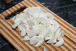 Chopped fresh mozzarella cheese with kitchen knife on wooden cutting board. food preparation Process.