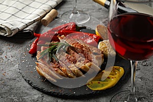 Chopped fried pork steak, vegetables and wine on background. Grilled food