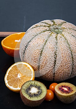 Chopped green and gold kiwis, orange halves, honeydew melons