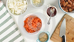 Chopped marinated pork meat and chopped vegetables close up on a kitchen table