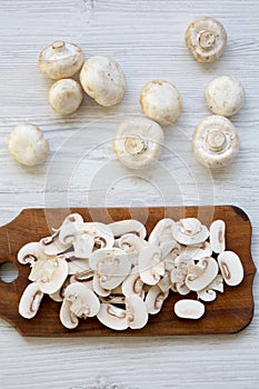 Chopped mushrooms on wooden chopping board, top view. White wooden background.