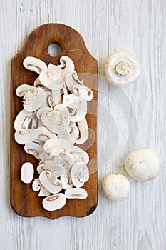 Chopped mushrooms on wooden chopping board, view from above. White wooden background. Overhead