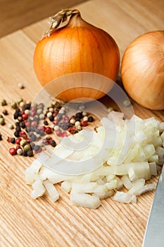 Chopped Onion on Wooden Cutting Board with Knife and Pepper