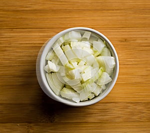 Chopped onions on wooden cutting board, top view