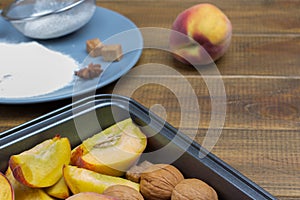 Chopped peaches and walnuts in baking sheet. Sieve and flour on plate