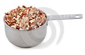 Chopped pecan nuts in a metal cup measure