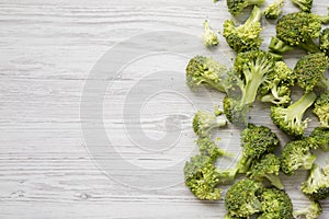 Chopped raw broccoli on white wooden table, top view.