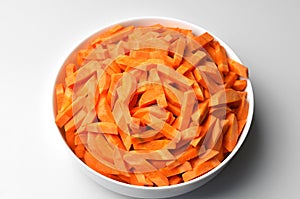 Chopped raw carrot root in big plate over white table background. Vegitarian food. Mediterranean diet