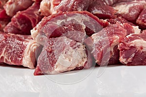 Chopped raw pork meat on white glass close-up.