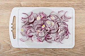 Chopped red onion on cutting board on wooden table