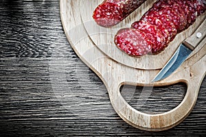 Chopped salami knife on wooden carving board