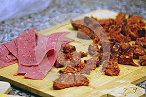 Chopped sausage and jambon on cutting board close up view preparation for the pizza