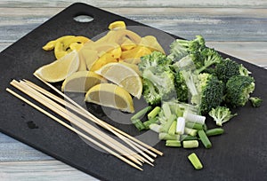 Chopped and sliced vegetables on cutting board with skewers